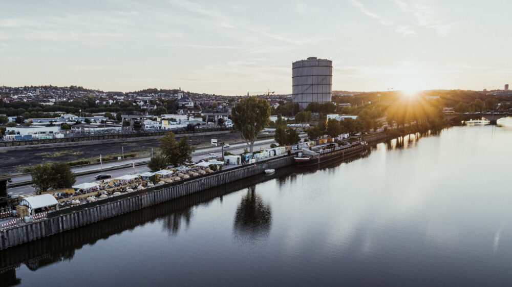 Luftaufnahme von Fridas Pier am Neckar in Stuttgart, mit Blick auf das gesamte Event‑ und Clubschiff und die umliegende Industriearchitektur.