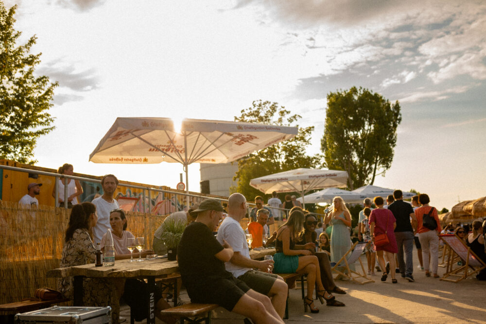 Menschen im Piergarten von Fridas Pier bei sommerlicher Stimmung mit Blick auf den Neckar.