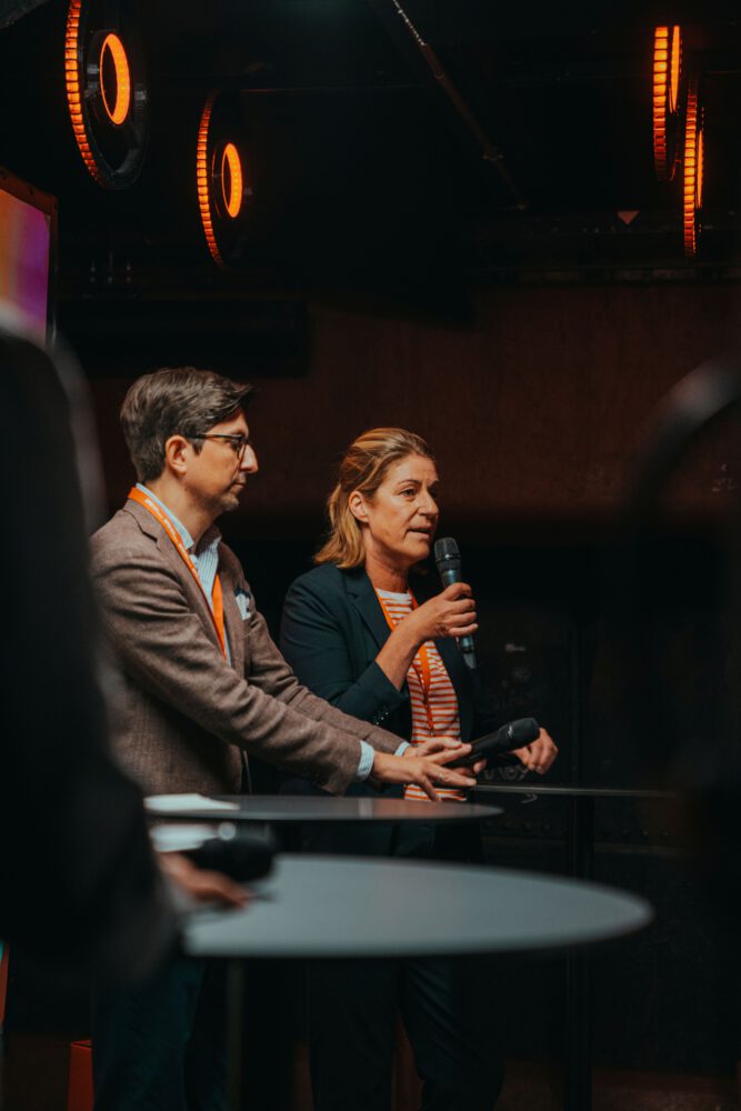 Moderierte Vortragssituation im Unterdeck von Fridas Pier mit Mikrofon und industrieller Beleuchtung.
